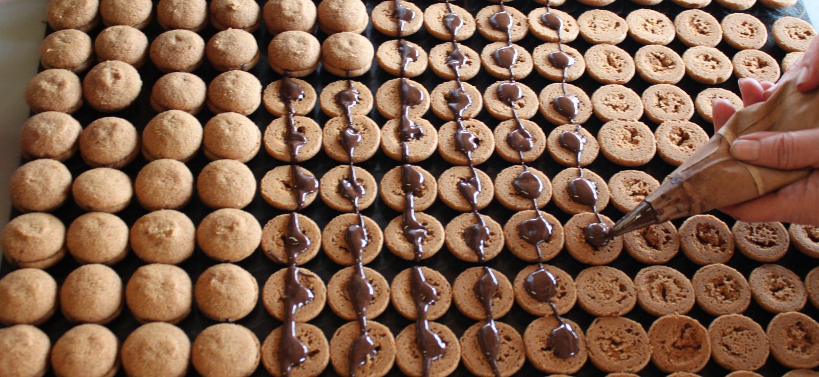 Filling the baci di dama with dark chocolate by hand